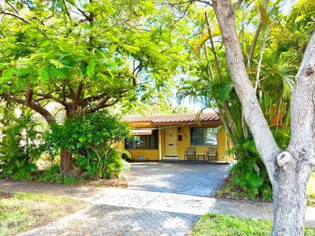 1124 NE 7th Street, Hallandale Beach, Hallandale Beach, FL 33009 Exterior facade featuring a terracotta-style tile roof, stucco finish, paved driveway, and mature landscaping