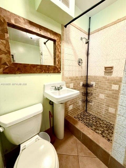 1124 NE 7th Street, Hallandale Beach, Hallandale Beach, FL 33009 Pedestal sink with dual-handle faucet, shower enclosure with pebble tile flooring and tiled walls, and rectangular wall-mounted mirror
