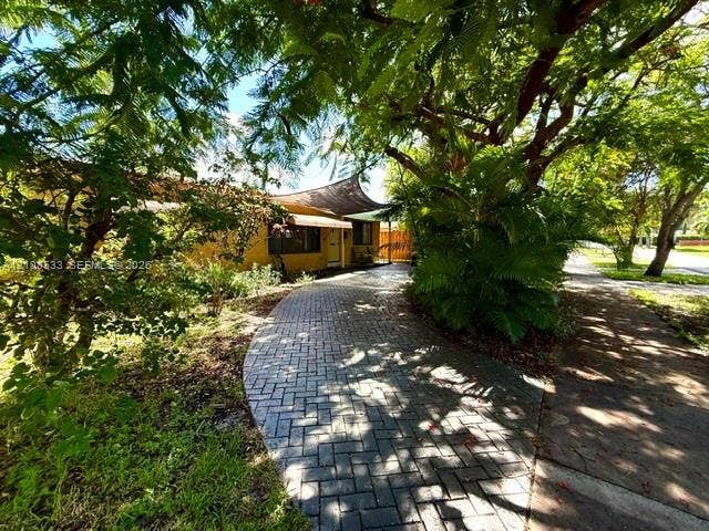 1124 NE 7th Street, Hallandale Beach, Hallandale Beach, FL 33009 Paved brick driveway featuring a fabric shade structure and established mature trees