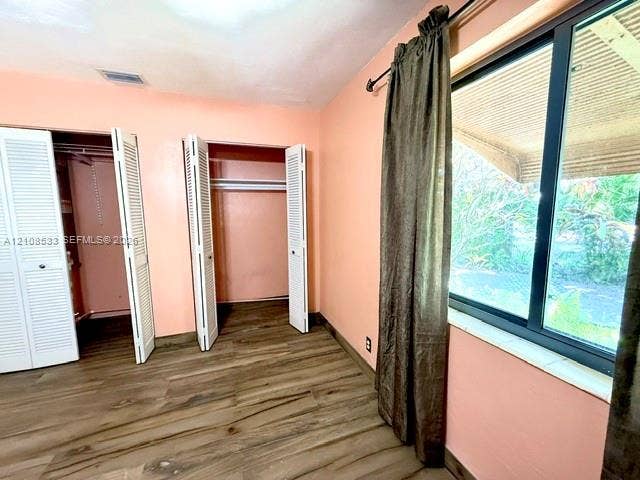 1124 NE 7th Street, Hallandale Beach, Hallandale Beach, FL 33009 Room featuring wood-finish flooring, dual closets with louvered doors, and a large window with a stone sill