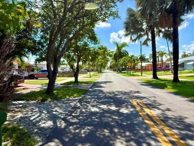 1124 NE 7th Street, Hallandale Beach, Hallandale Beach, FL 33009 Paved streetscape featuring mature palm trees, established shade trees, and paver stone driveway accents