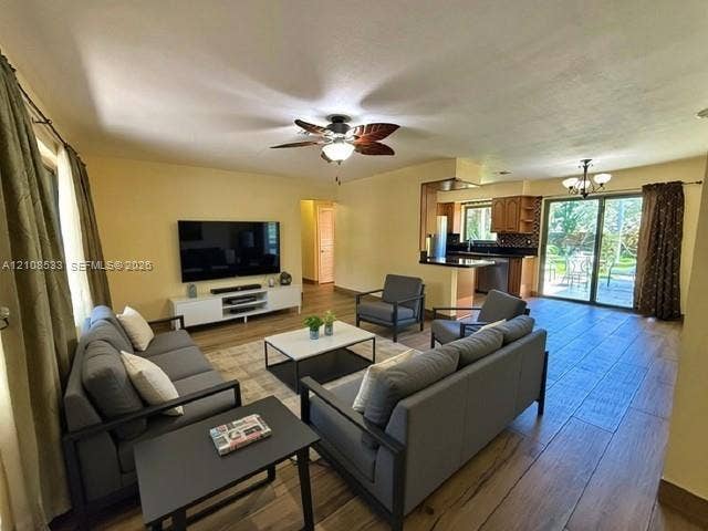 1124 NE 7th Street, Hallandale Beach, Hallandale Beach, FL 33009 Open floor plan featuring wood-finish flooring, ceiling fan with light fixture, kitchen with cabinetry and dark countertops, and sliding glass doors