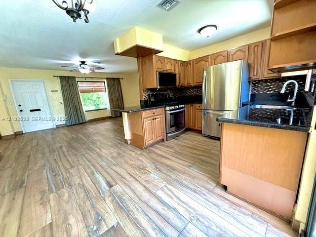 1124 NE 7th Street, Hallandale Beach, Hallandale Beach, FL 33009 Kitchen featuring wood-finish flooring, stainless steel appliances, dark stone-composite countertops, and wood cabinetry