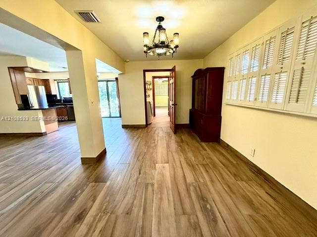 1124 NE 7th Street, Hallandale Beach, Hallandale Beach, FL 33009 Interior space featuring wood-finish flooring, a multi-arm candelabra chandelier, and plantation shutters