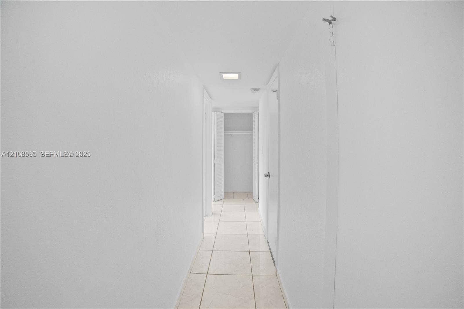 Hallway featuring neutral-toned tile flooring, recessed lighting, and built-in closet storage