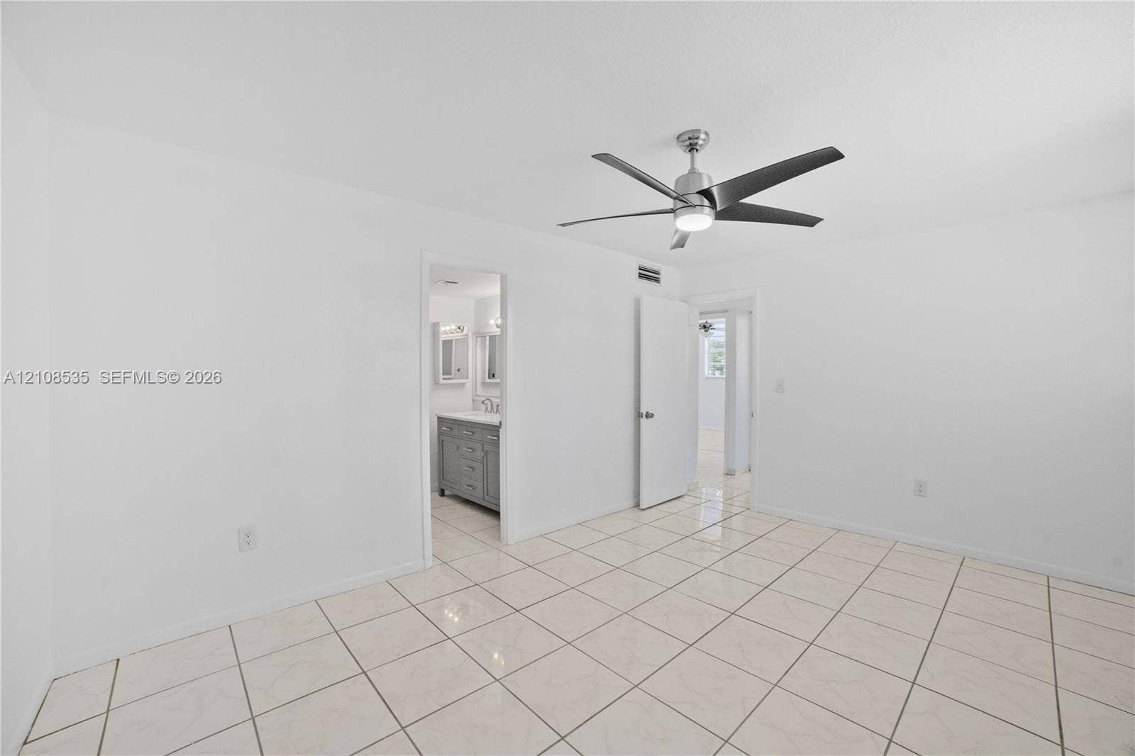 Interior room featuring light-toned tile flooring and a multi-blade ceiling fan with an integrated light fixture