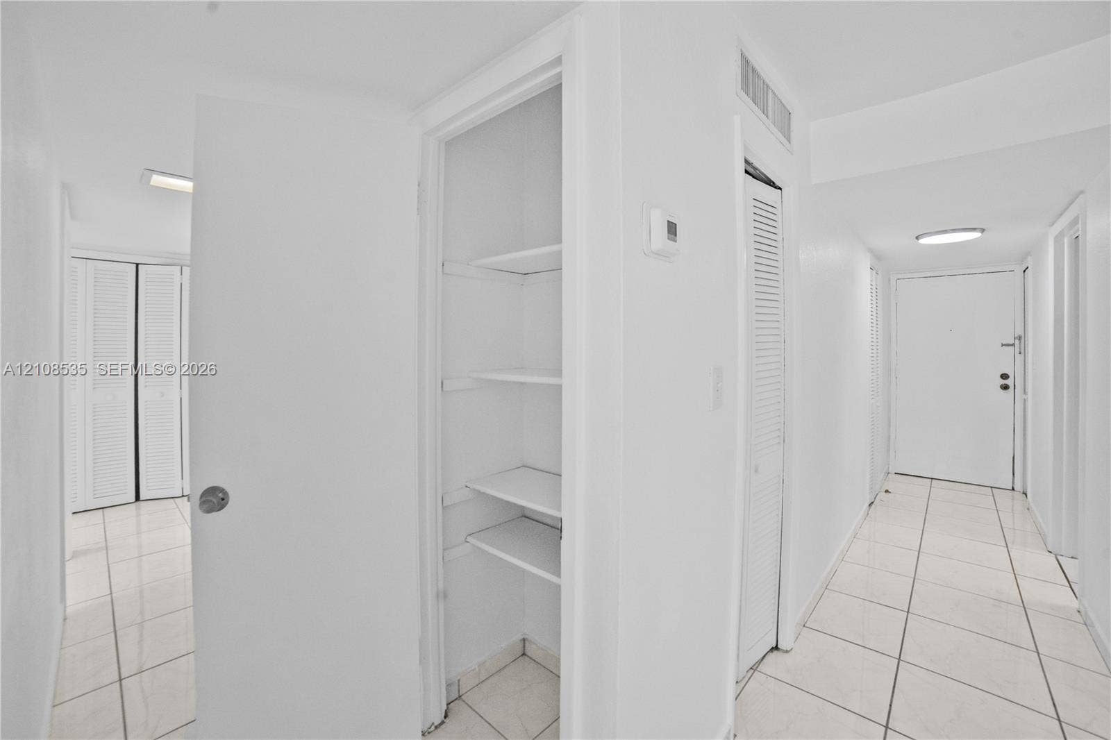 Ceramic tile flooring, louvered closet doors, and open-shelf built-in storage