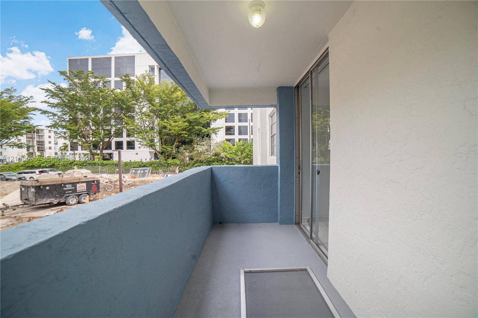 Private covered balcony featuring painted masonry walls, durable floor surfacing, flush-mount lighting, and sliding glass door entry