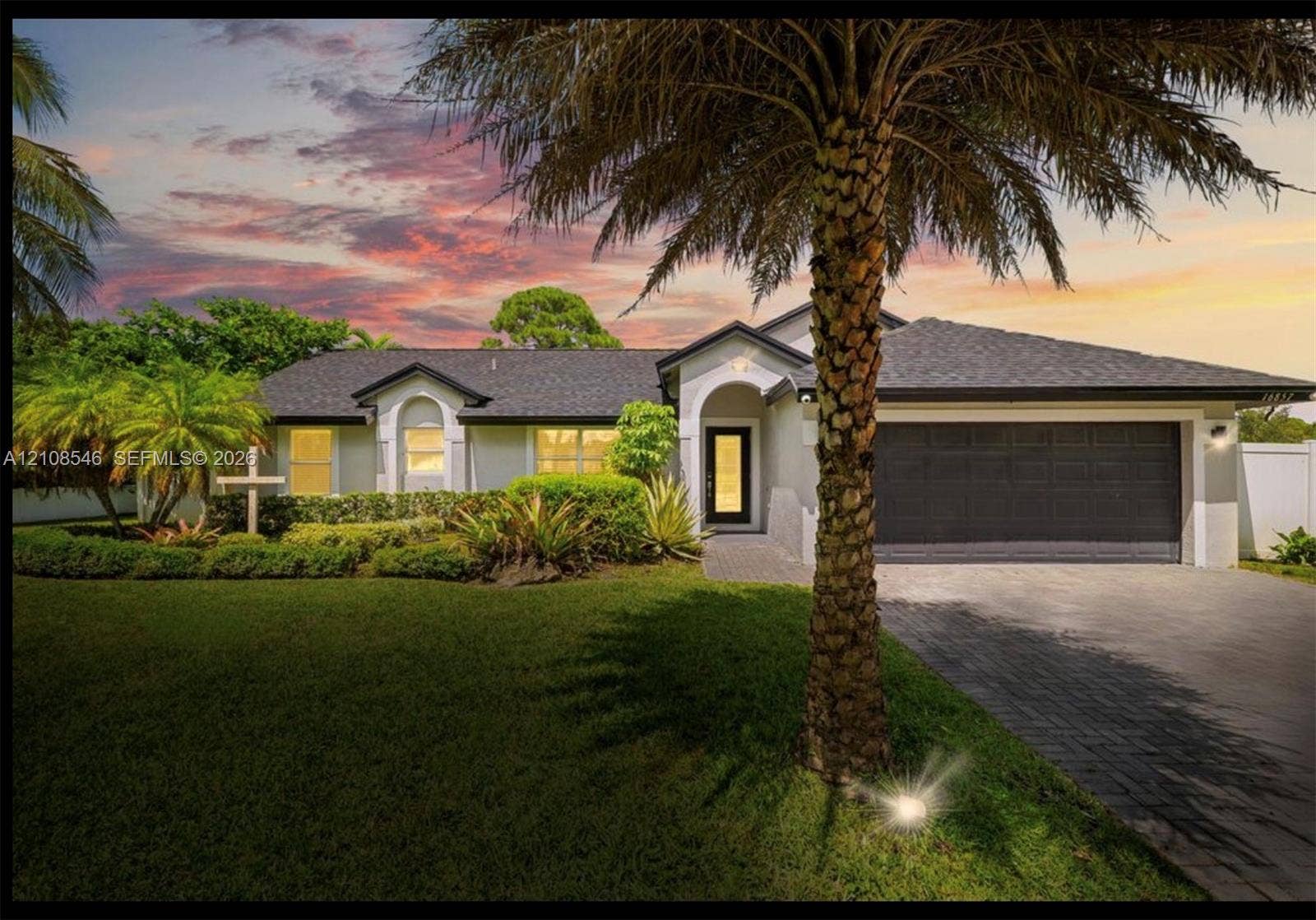 Single-story exterior featuring a hip roof, arched entryway, paved driveway, and integrated garage with a multi-panel door