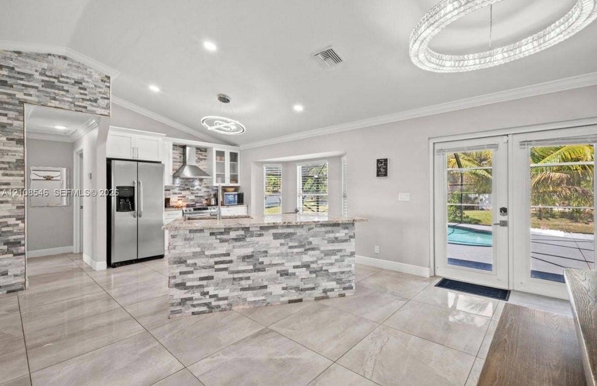 Kitchen featuring a stacked stone kitchen island, stainless steel refrigerator, tile flooring, recessed lighting, and double glass doors