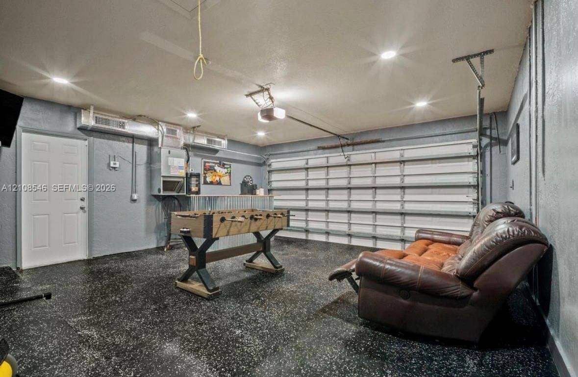 Garage space featuring an epoxy-coated floor, recessed lighting, a sectional garage door, and a dedicated service door