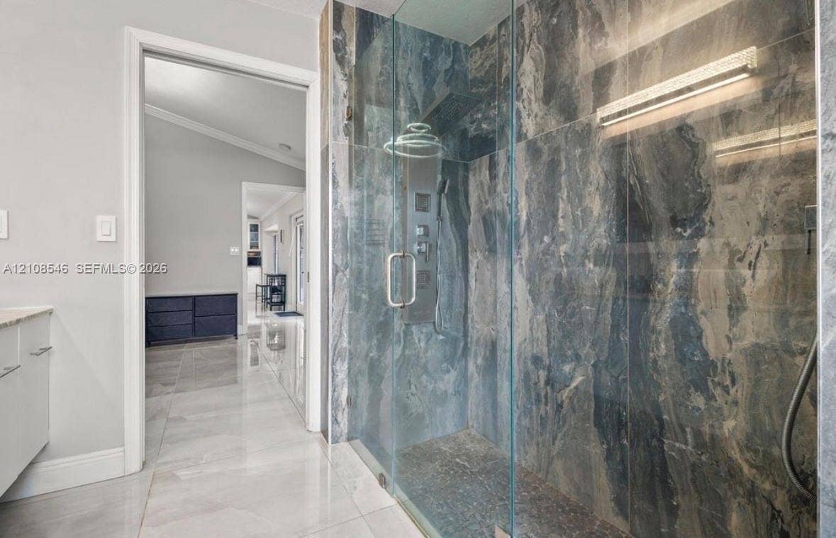 Walk-in shower featuring floor-to-ceiling stone-finish wall tile, frameless glass enclosure, multi-function shower panel, and light-tone large-format floor tile