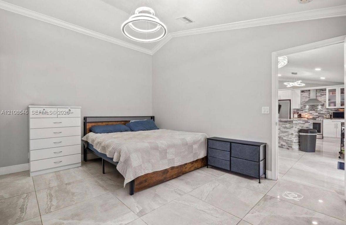 Neutral-toned interior featuring large-format tile flooring, vaulted ceilings with crown molding, and a contemporary circular LED pendant light fixture