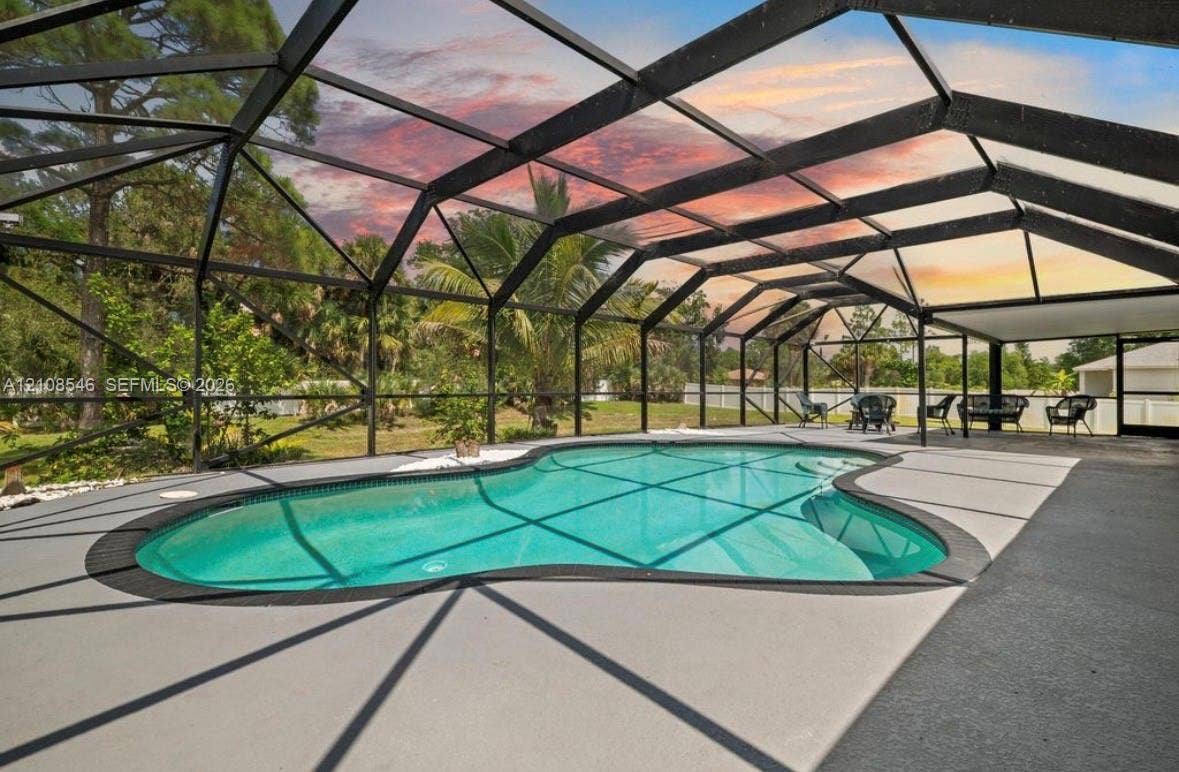Screened-in patio featuring a freeform swimming pool, concrete deck, and perimeter fencing