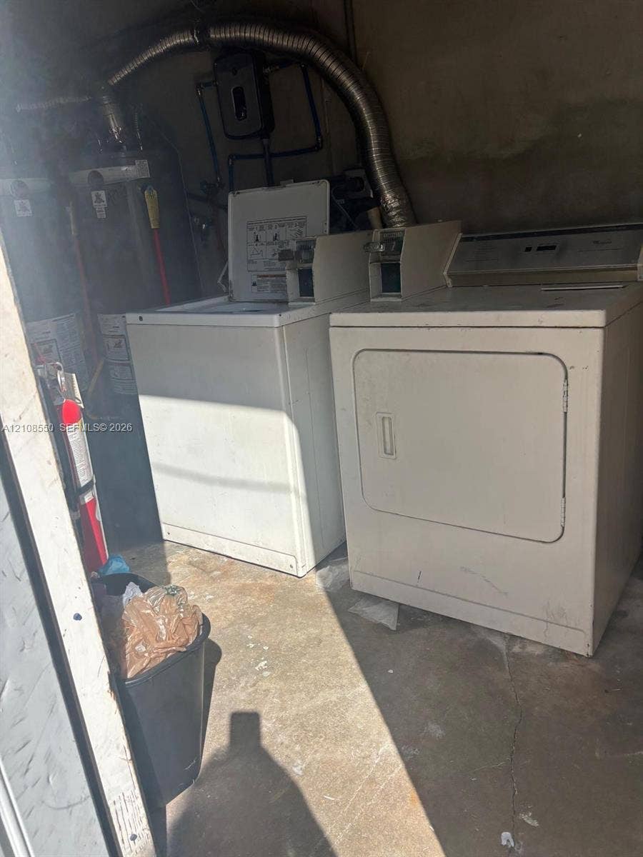 Dedicated laundry space featuring a top-load washer, a front-load dryer, and an integrated water heater unit with metal venting