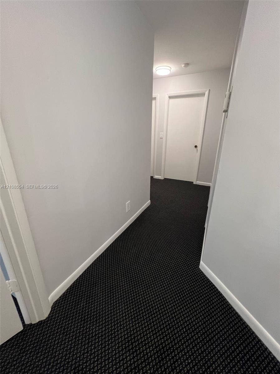 Hallway featuring patterned wall-to-wall carpeting, neutral-toned walls, and recessed ceiling lighting
