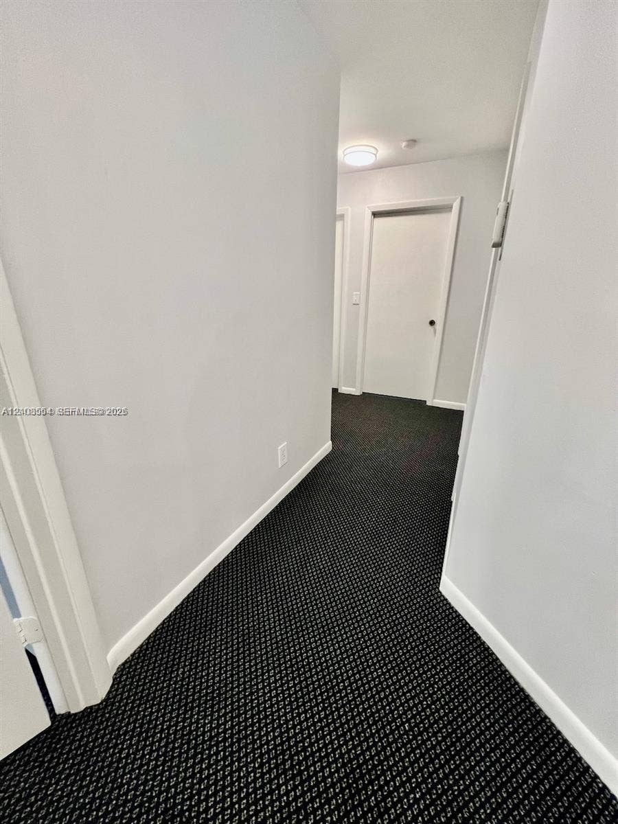 Hallway featuring patterned carpeting, neutral wall color, and flush-mount ceiling lighting