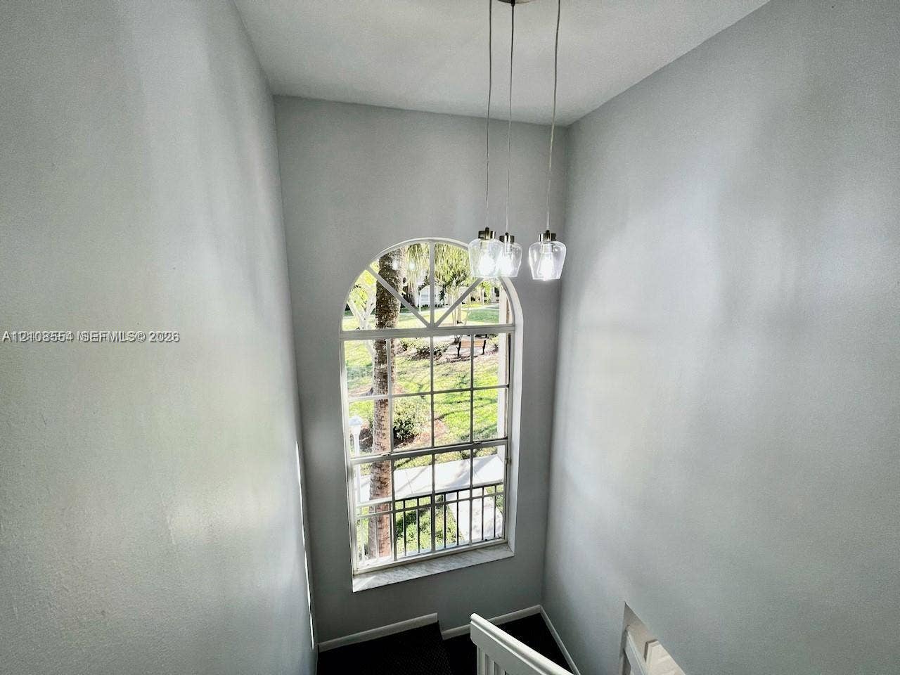 Multi-story space featuring an arched multi-pane window and a three-light pendant fixture