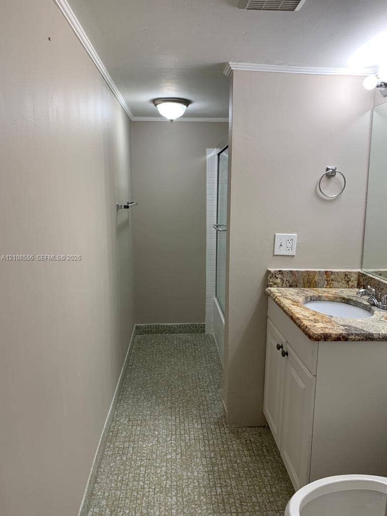 600 SW 2nd Avenue, #137, Boca Raton, FL 33432 Bathroom featuring a stone-look countertop, integrated vanity cabinet, flush-mount ceiling lighting, and a shower enclosure with a glass door