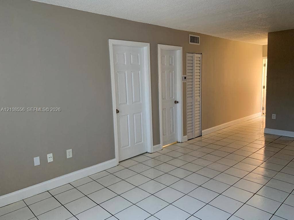 600 SW 2nd Avenue, #137, Boca Raton, FL 33432 Neutral-toned interior featuring white ceramic floor tile, two interior paneled doors, and a louvered closet door
