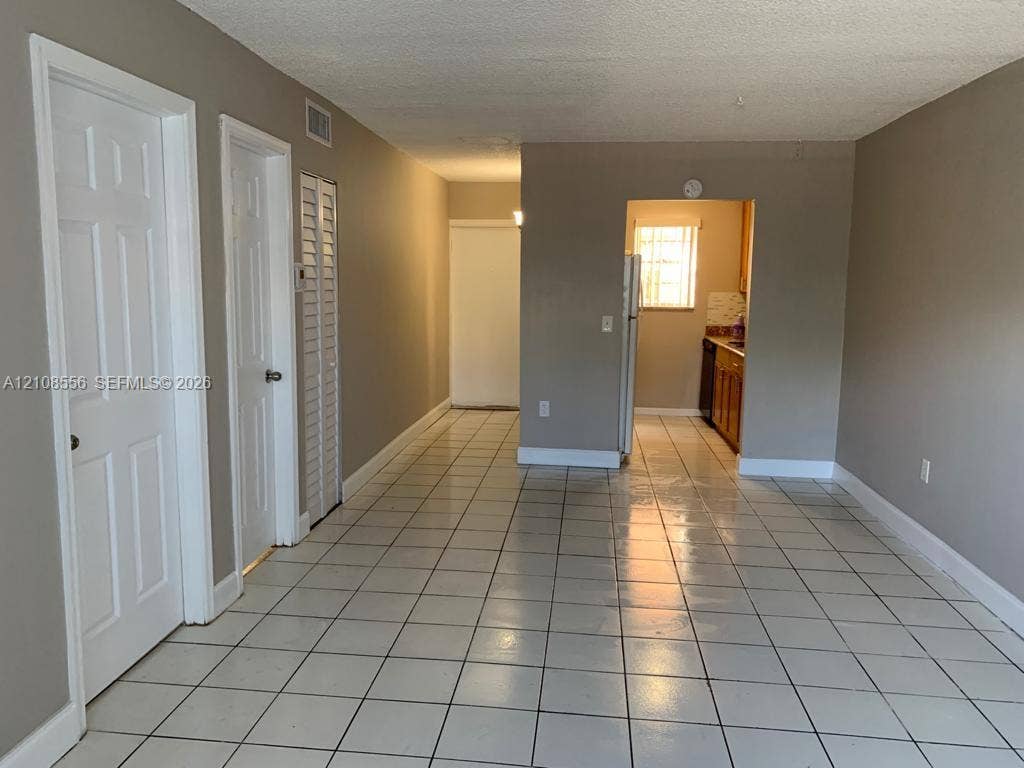 600 SW 2nd Avenue, #137, Boca Raton, FL 33432 Neutral-toned interior featuring ceramic tile flooring, solid-core interior doors, louvered closet doors, and recessed kitchen cabinetry