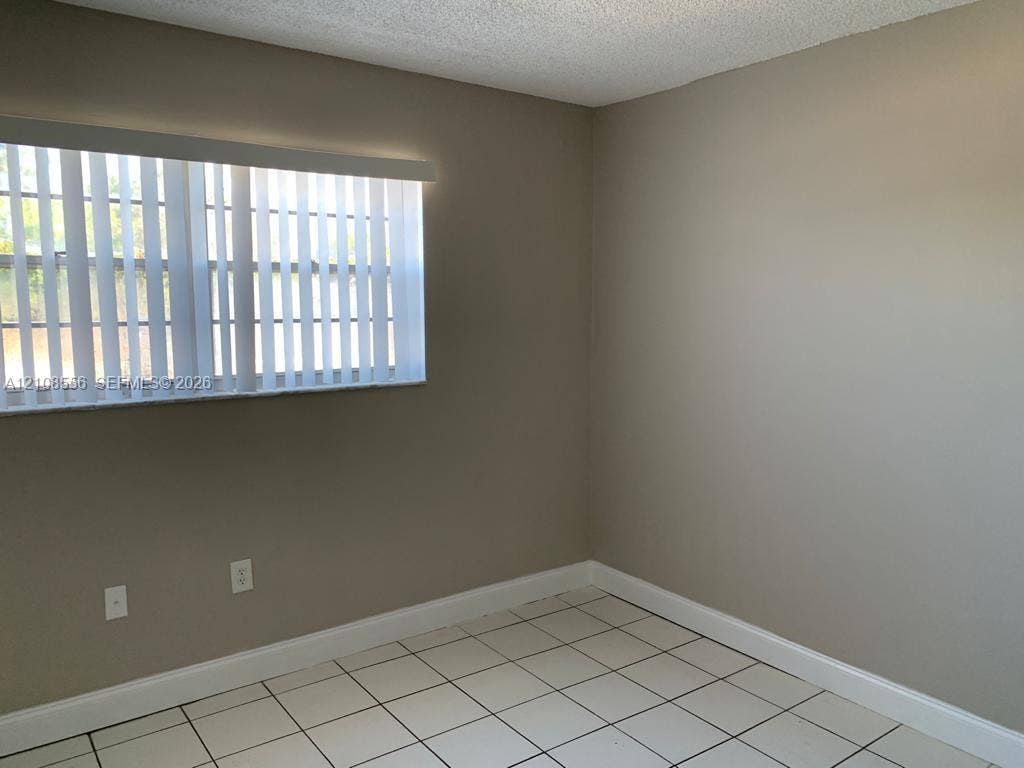 600 SW 2nd Avenue, #137, Boca Raton, FL 33432 Neutral-toned interior room featuring white tile flooring, vertical window blinds, and textured ceiling finish