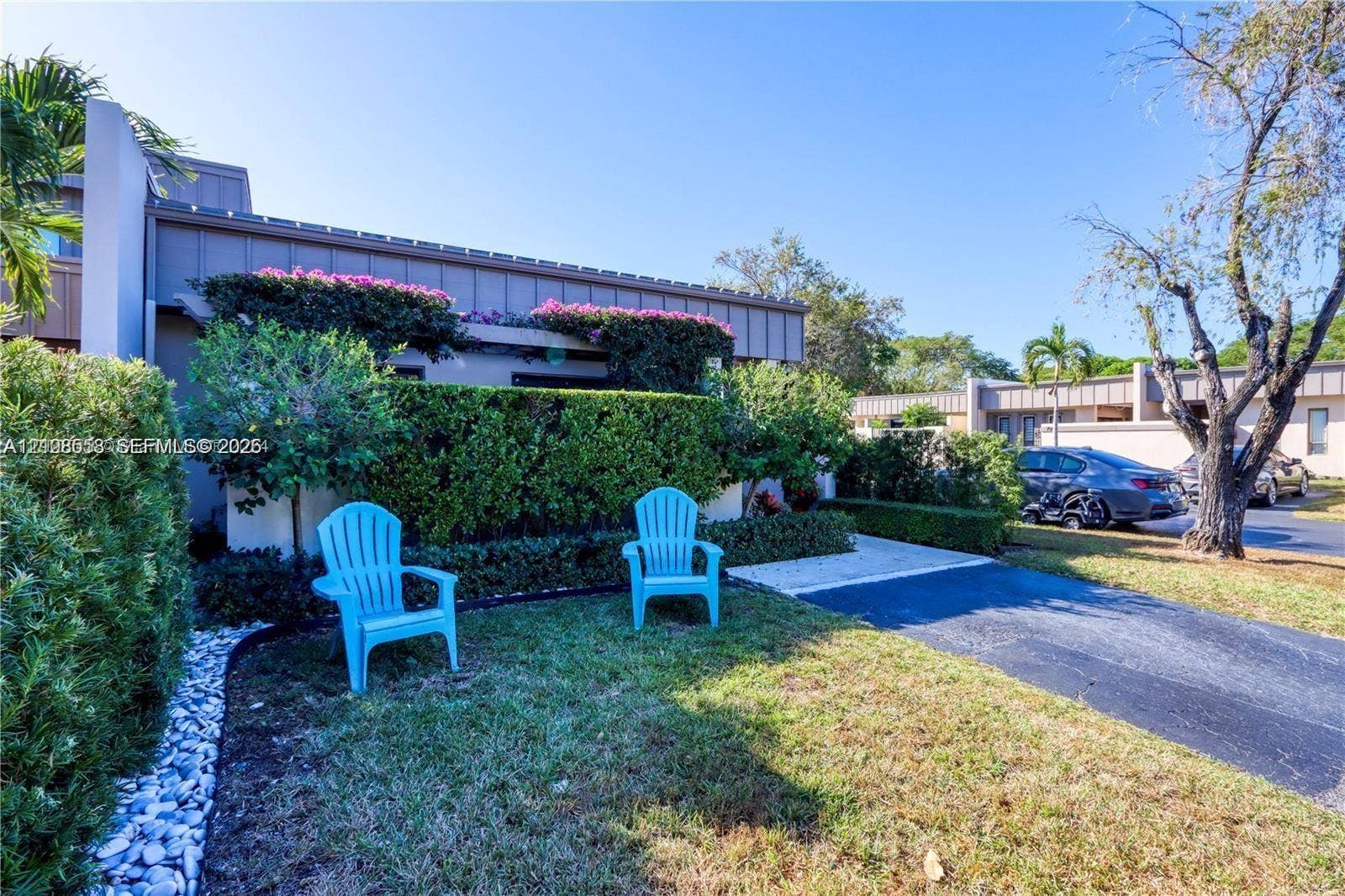 10478 SW 75th Lane, #10478, Miami, Miami, FL 33173 Exterior elevation featuring vertical wood-style siding, manicured shrubbery, decorative stone edging, and a paved driveway