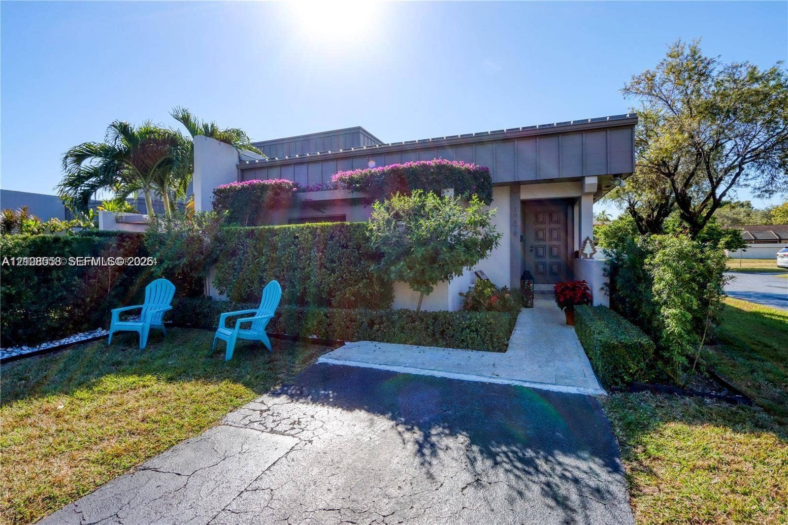 10478 SW 75th Lane, #10478, Miami, Miami, FL 33173 Exterior featuring a flat roofline with metal trim, paneled entry door, concrete walkway, and mature landscaping