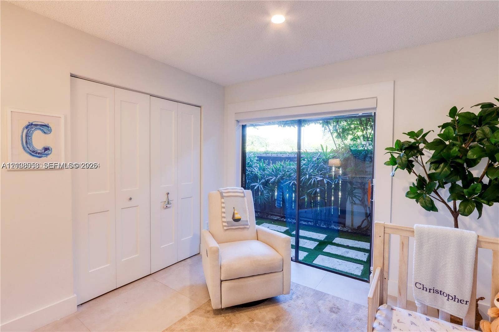 10478 SW 75th Lane, #10478, Miami, Miami, FL 33173 Interior space featuring large format light-toned tile flooring, floor-to-ceiling bifold closet doors, and a sliding glass door providing external access