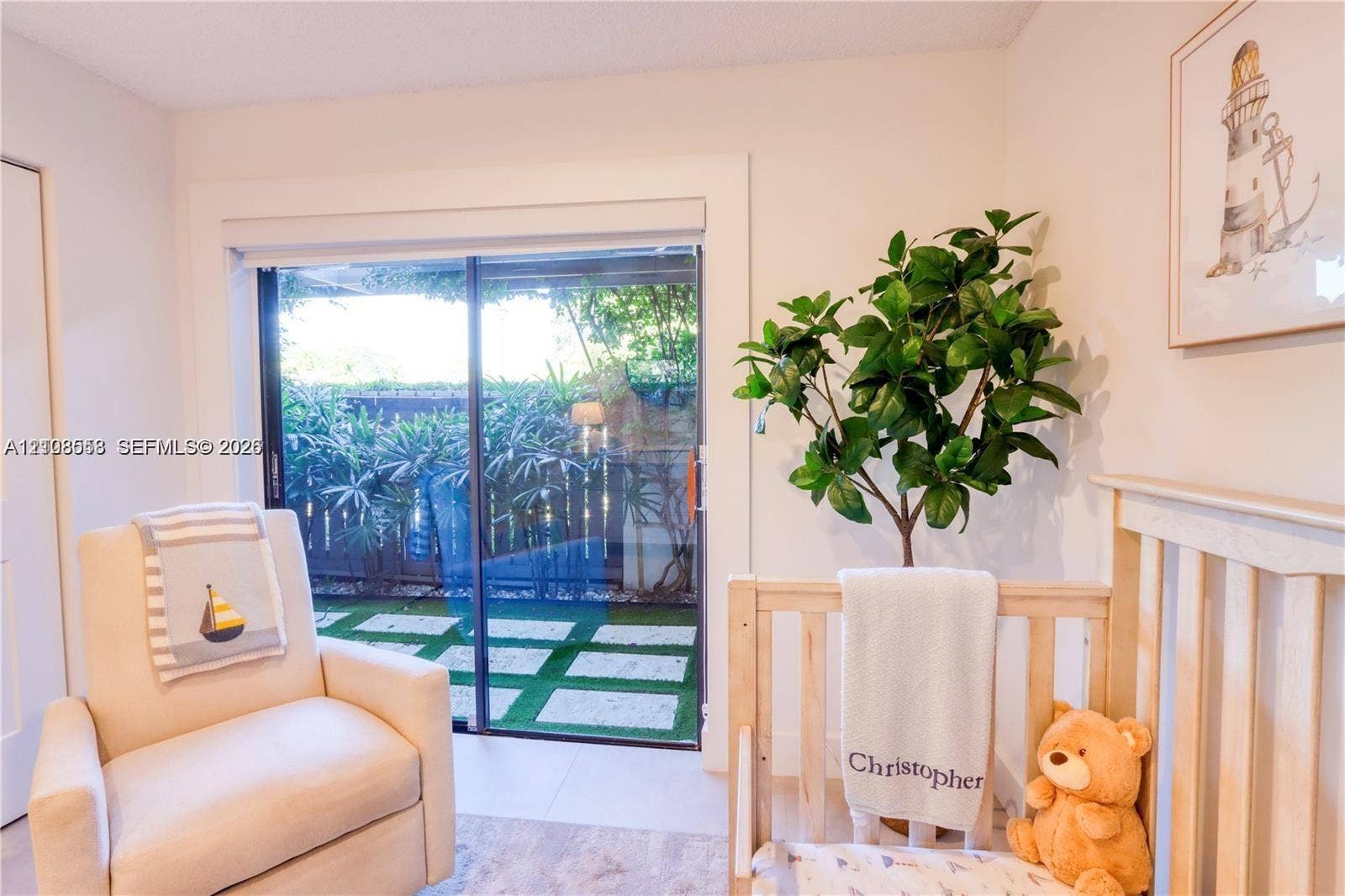 10478 SW 75th Lane, #10478, Miami, Miami, FL 33173 Sliding glass door with wide casing, stone-tile flooring, and access to a fenced patio area featuring stone pavers set in artificial turf