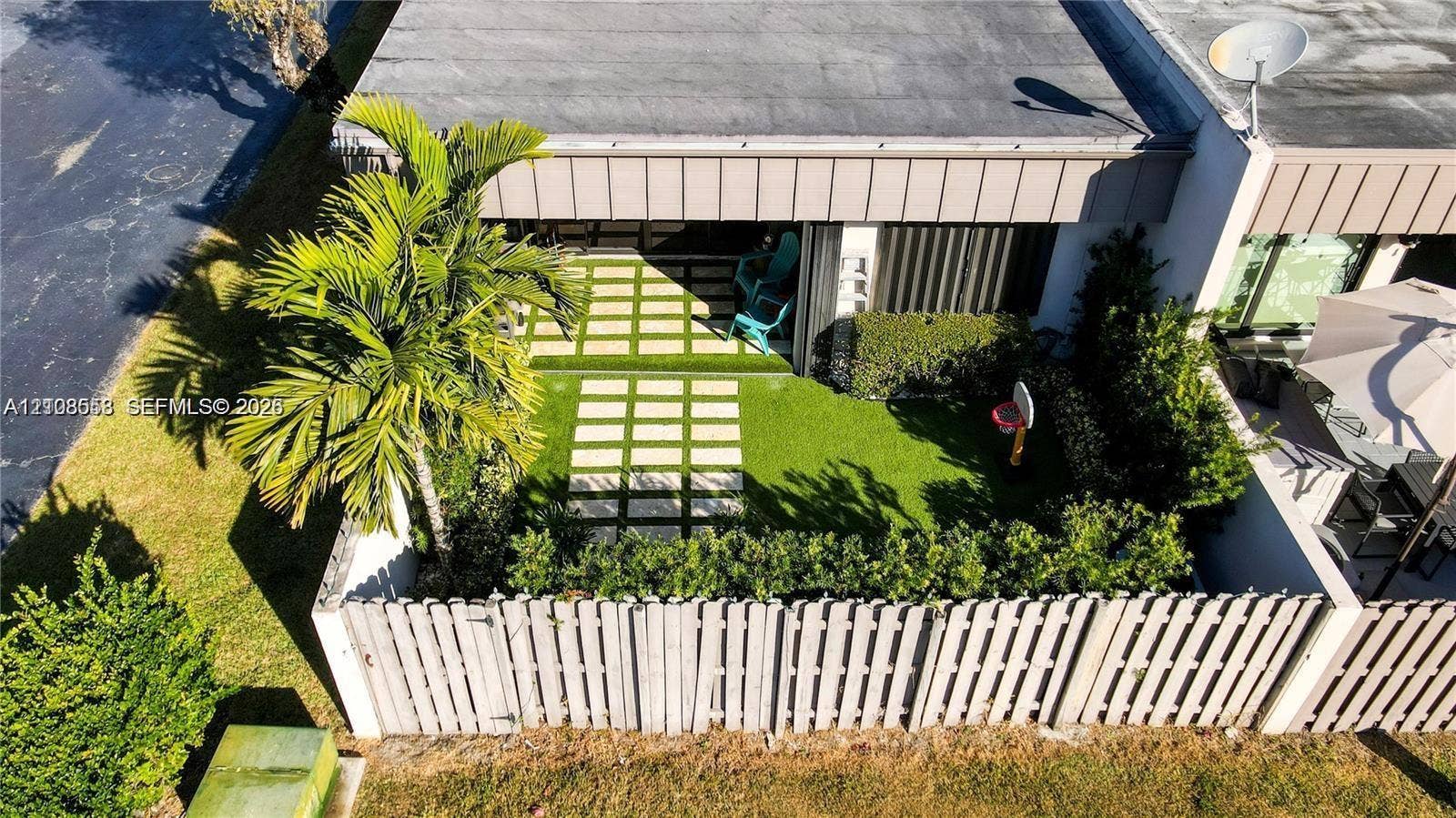 10478 SW 75th Lane, #10478, Miami, Miami, FL 33173 Private rear courtyard featuring a wooden privacy fence, stone paver path, manicured lawn, and palm tree landscaping