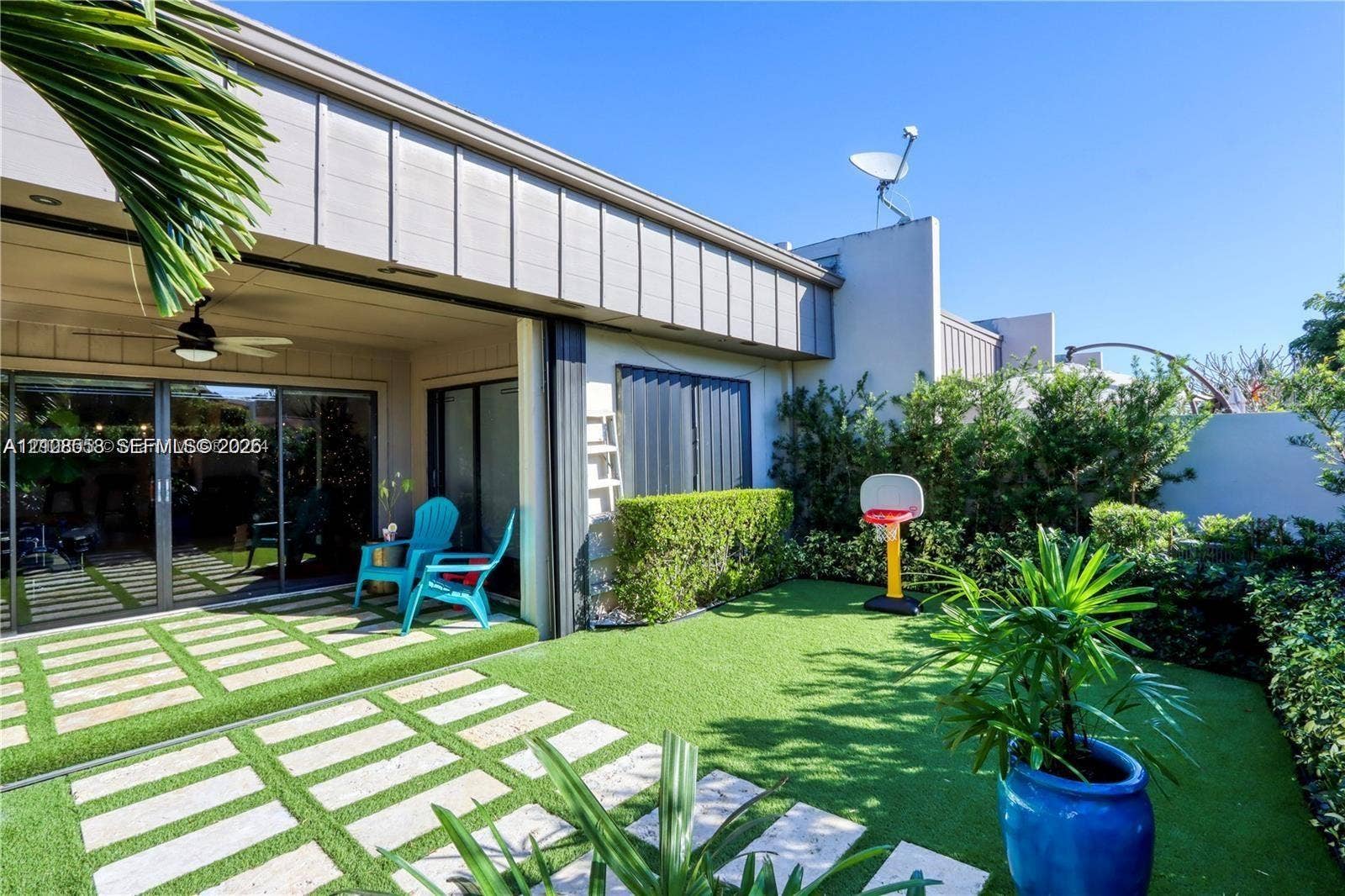 10478 SW 75th Lane, #10478, Miami, Miami, FL 33173 Private patio featuring synthetic turf, paver hardscaping, integrated ceiling fan, and perimeter hedge landscaping