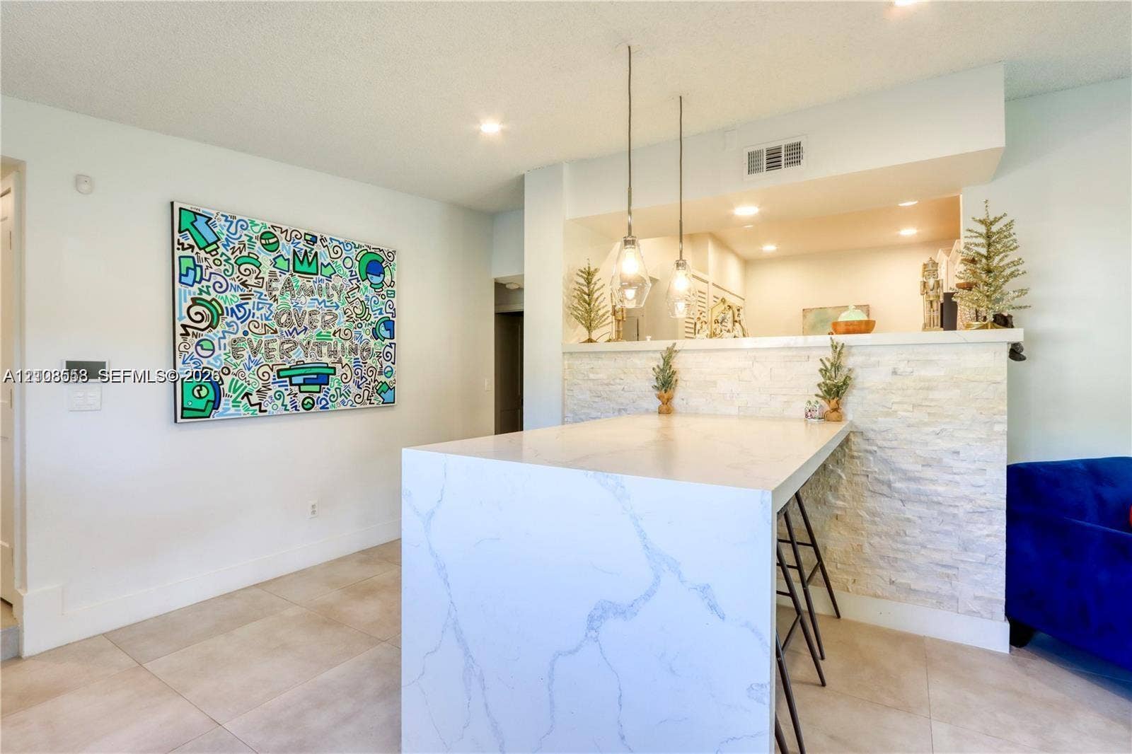 10478 SW 75th Lane, #10478, Miami, Miami, FL 33173 Kitchen island featuring a stone-finish waterfall countertop, stacked stone facade, dual pendant lighting, and neutral tile flooring