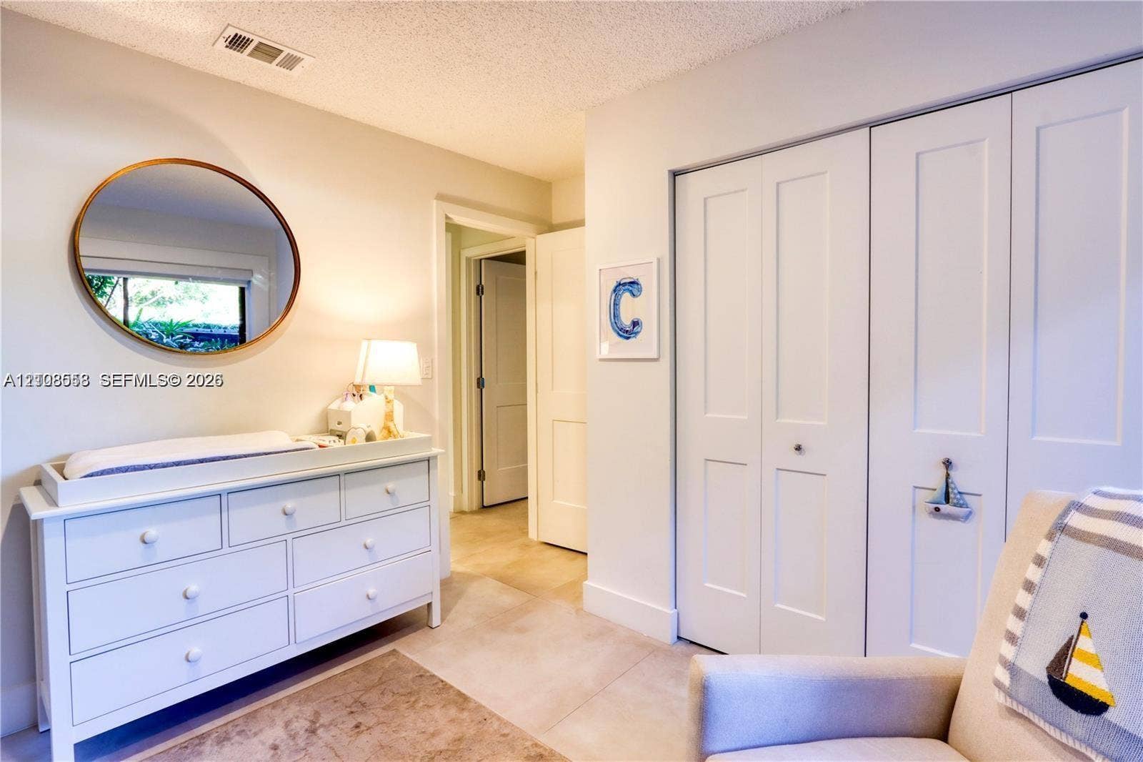 10478 SW 75th Lane, #10478, Miami, Miami, FL 33173 Neutral-toned interior featuring smooth-finish ceiling, large round wall mirror, and double-panel bifold closet doors