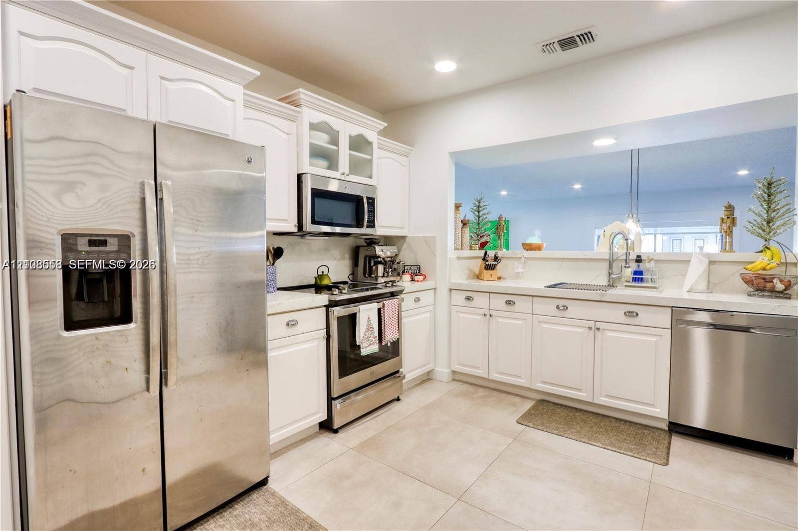 10478 SW 75th Lane, #10478, Miami, Miami, FL 33173 Kitchen featuring white cabinetry, stainless steel appliances, neutral stone-finish countertops, and large-format tile flooring