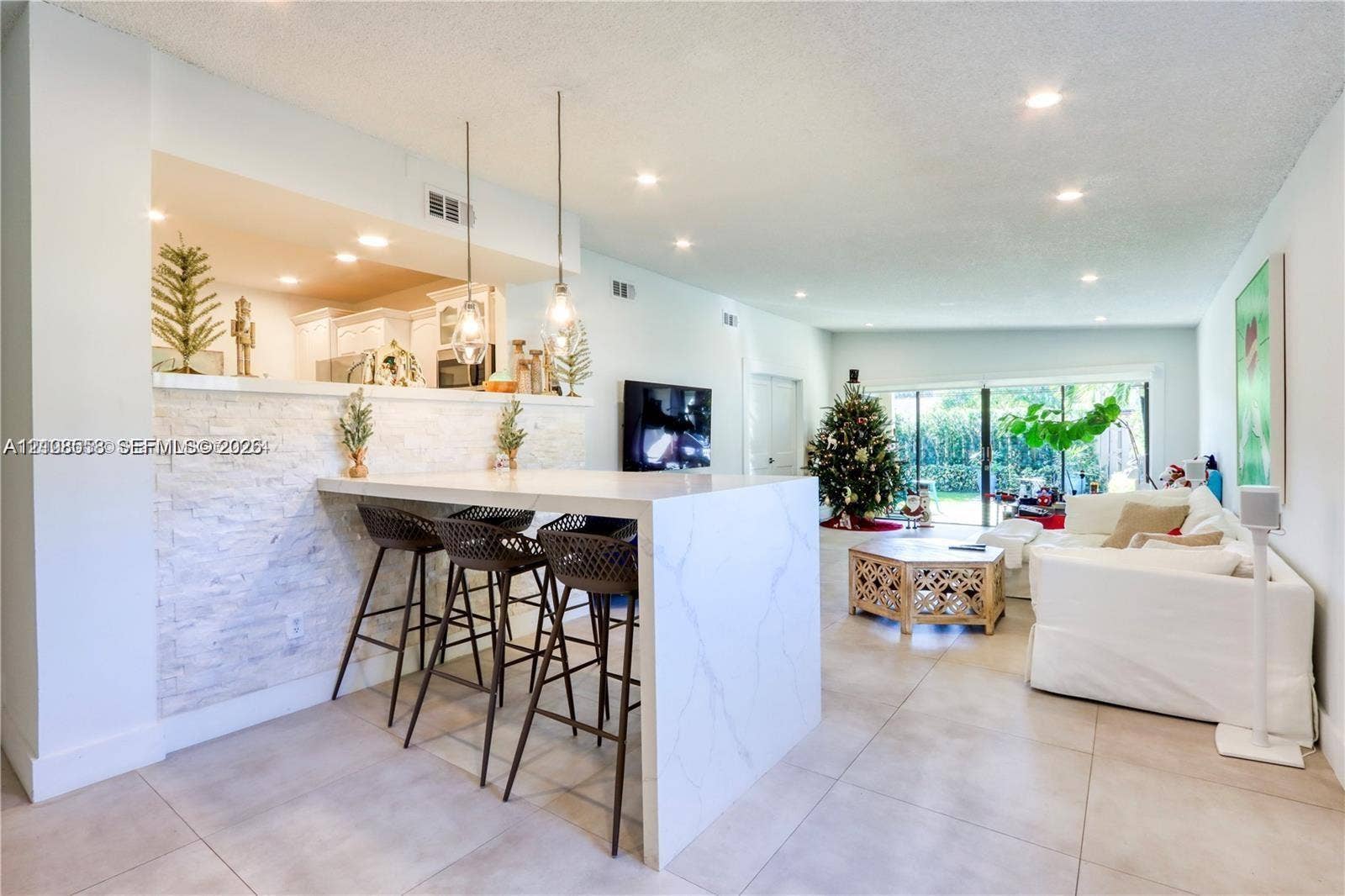 10478 SW 75th Lane, #10478, Miami, Miami, FL 33173 Kitchen island with a white stone-finish countertop, stacked stone facade, recessed lighting, and dual pendant light fixtures, finished with large-format tile flooring