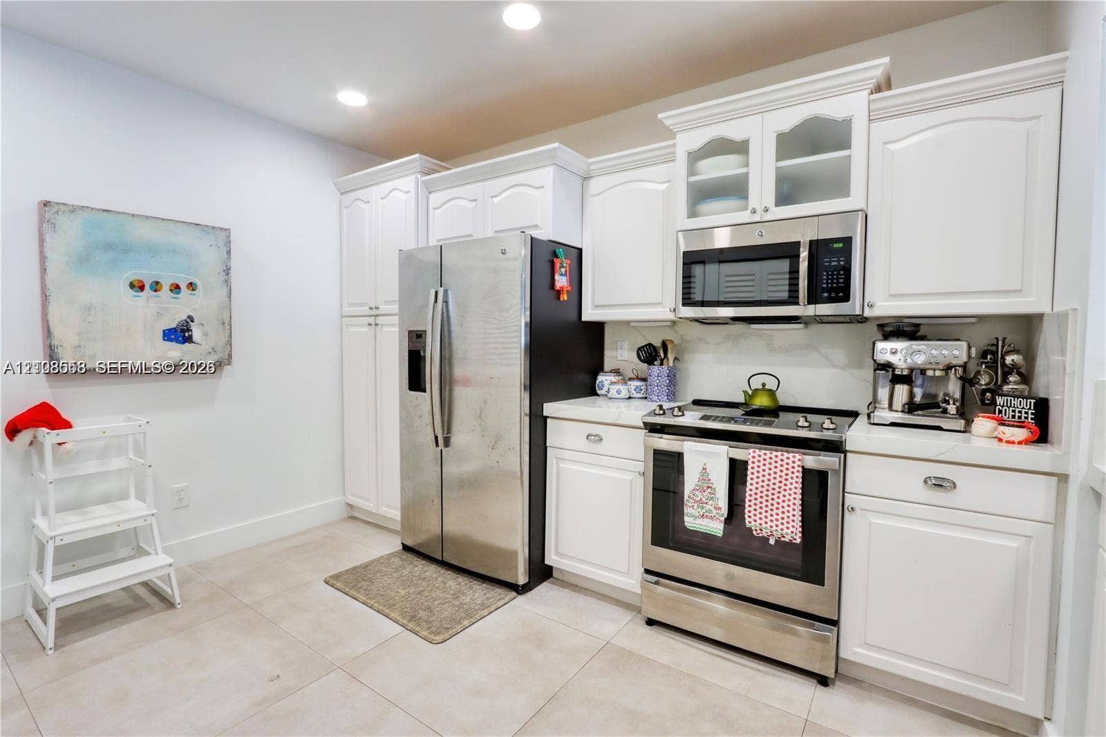 10478 SW 75th Lane, #10478, Miami, Miami, FL 33173 Kitchen featuring white cabinetry with glass-panel upper doors, stainless steel refrigerator, stainless steel range with overhead microwave, and stone-finish flooring
