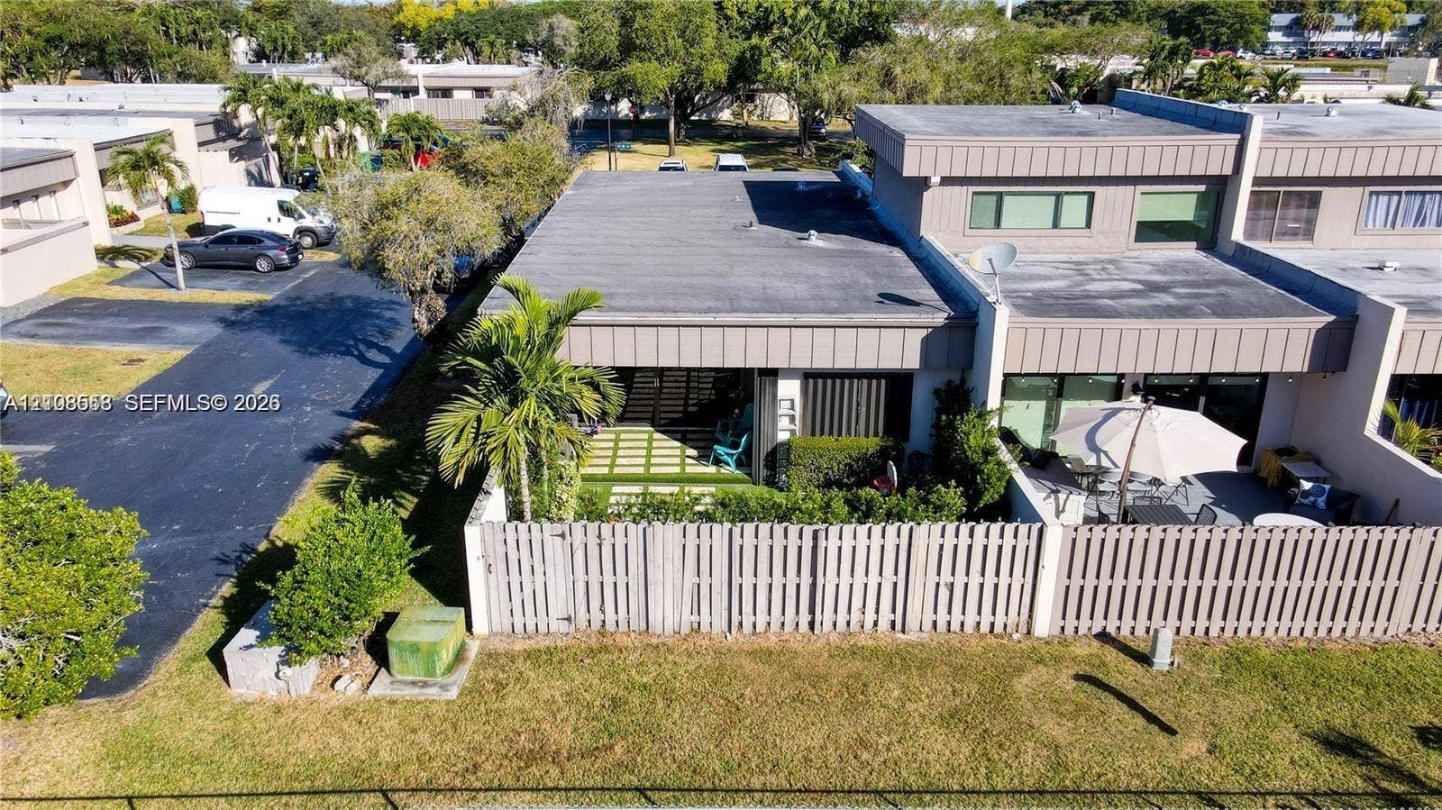 10478 SW 75th Lane, #10478, Miami, Miami, FL 33173 Multi-level exterior featuring a flat roofline, fenced patio area, ground-level paved terrace, and manicured landscaping