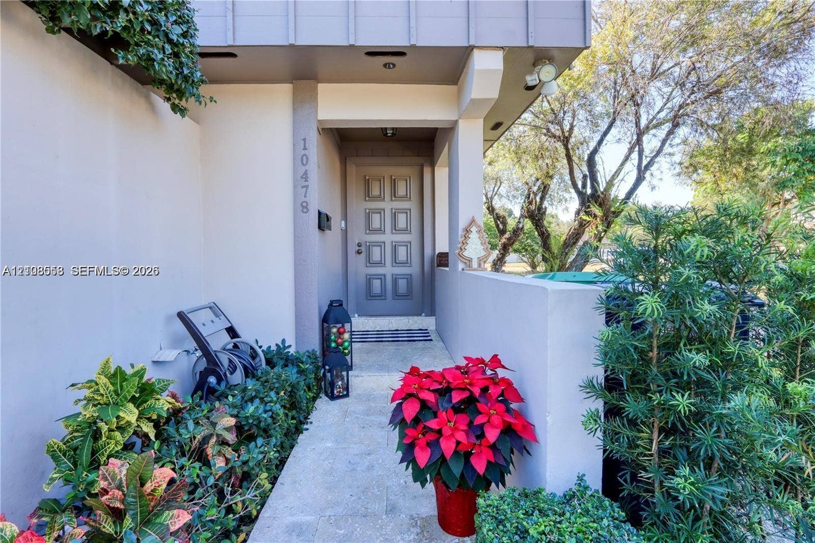 10478 SW 75th Lane, #10478, Miami, Miami, FL 33173 Covered entryway featuring an eight-panel entry door, exterior masonry wall, and paved walkway