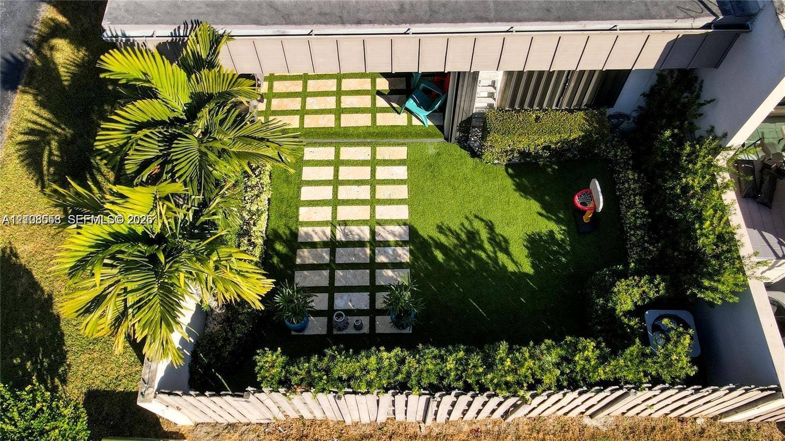 10478 SW 75th Lane, #10478, Miami, Miami, FL 33173 Enclosed backyard featuring a paver stone walkway, artificial turf lawn, mature palm trees, perimeter hedging, and wood-style privacy fencing
