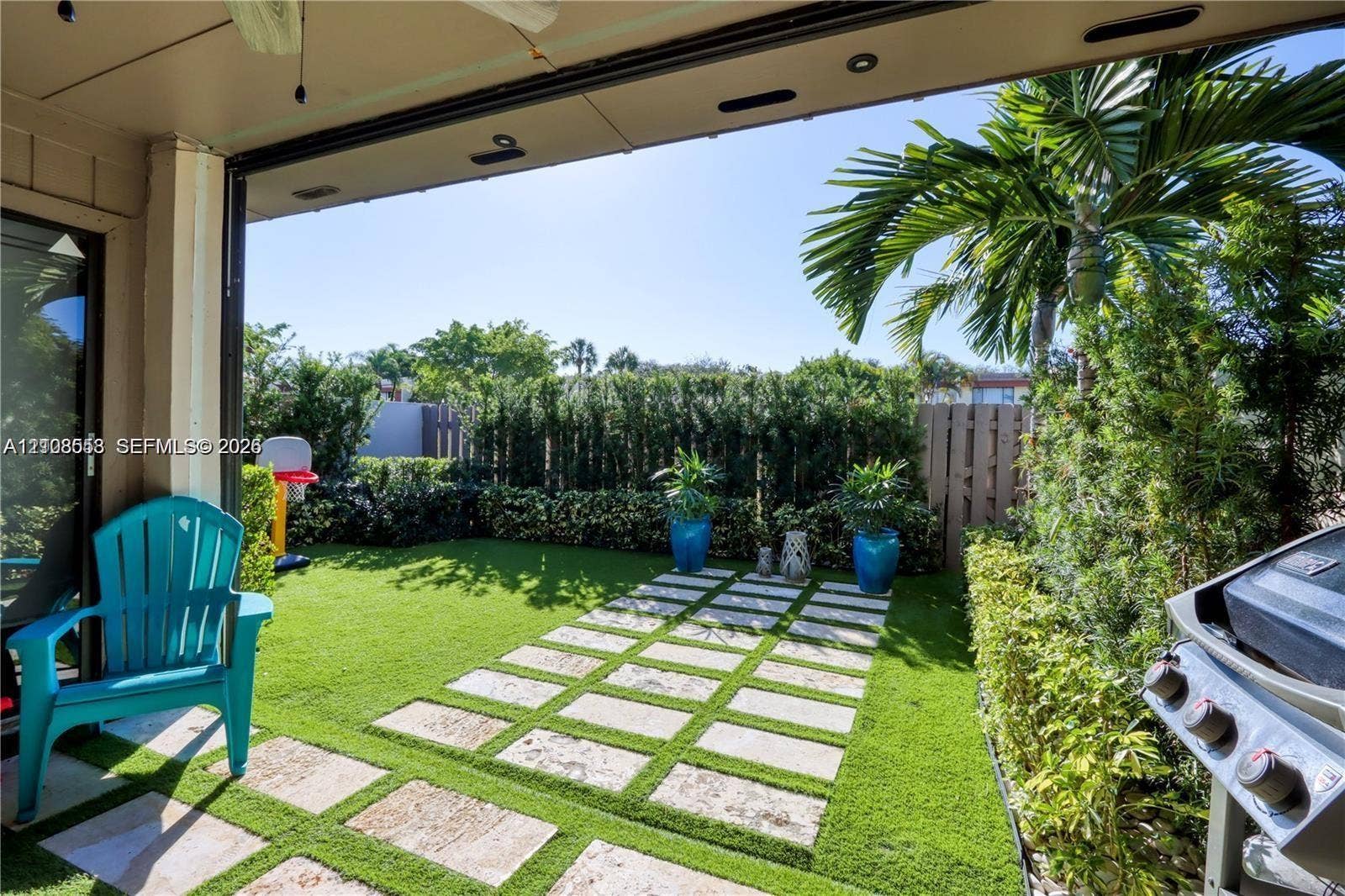 10478 SW 75th Lane, #10478, Miami, Miami, FL 33173 Covered patio featuring a paved walkway, synthetic turf, and perimeter privacy hedges