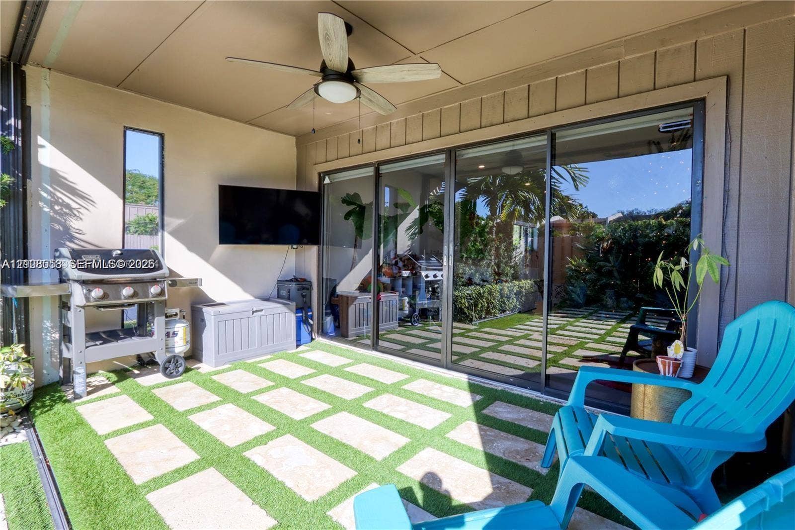 10478 SW 75th Lane, #10478, Miami, Miami, FL 33173 Covered patio featuring artificial turf, stone pavers, ceiling-mounted fan, and sliding glass wall system