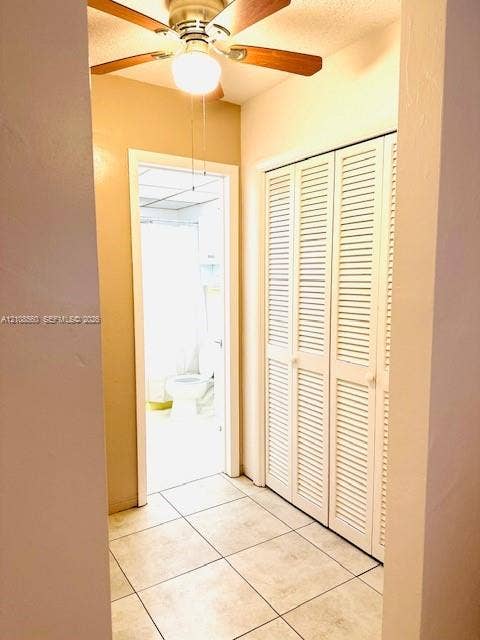 22 SE 3rd Terrace, #6, Dania, Dania Beach, FL 33004 Hallway featuring tile flooring, louvered bi-fold closet doors, and a ceiling-mounted fan with integrated lighting