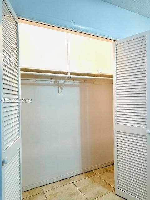 22 SE 3rd Terrace, #6, Dania, Dania Beach, FL 33004 Closet featuring white louvered bi-fold doors, overhead built-in cabinetry, and tile flooring