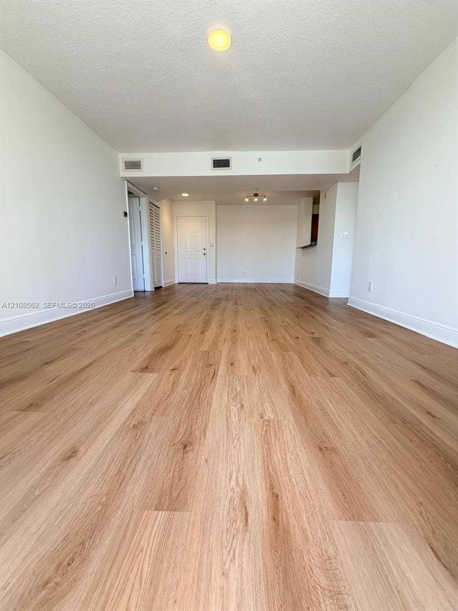 Open-concept interior featuring light wood-finish flooring, neutral walls, and flush-mount ceiling lighting