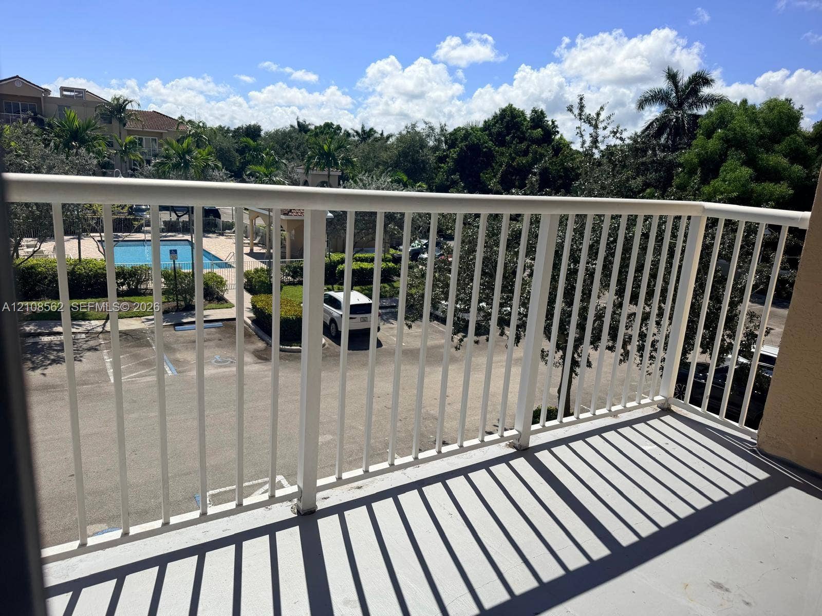 Private balcony with white metal railings and concrete flooring