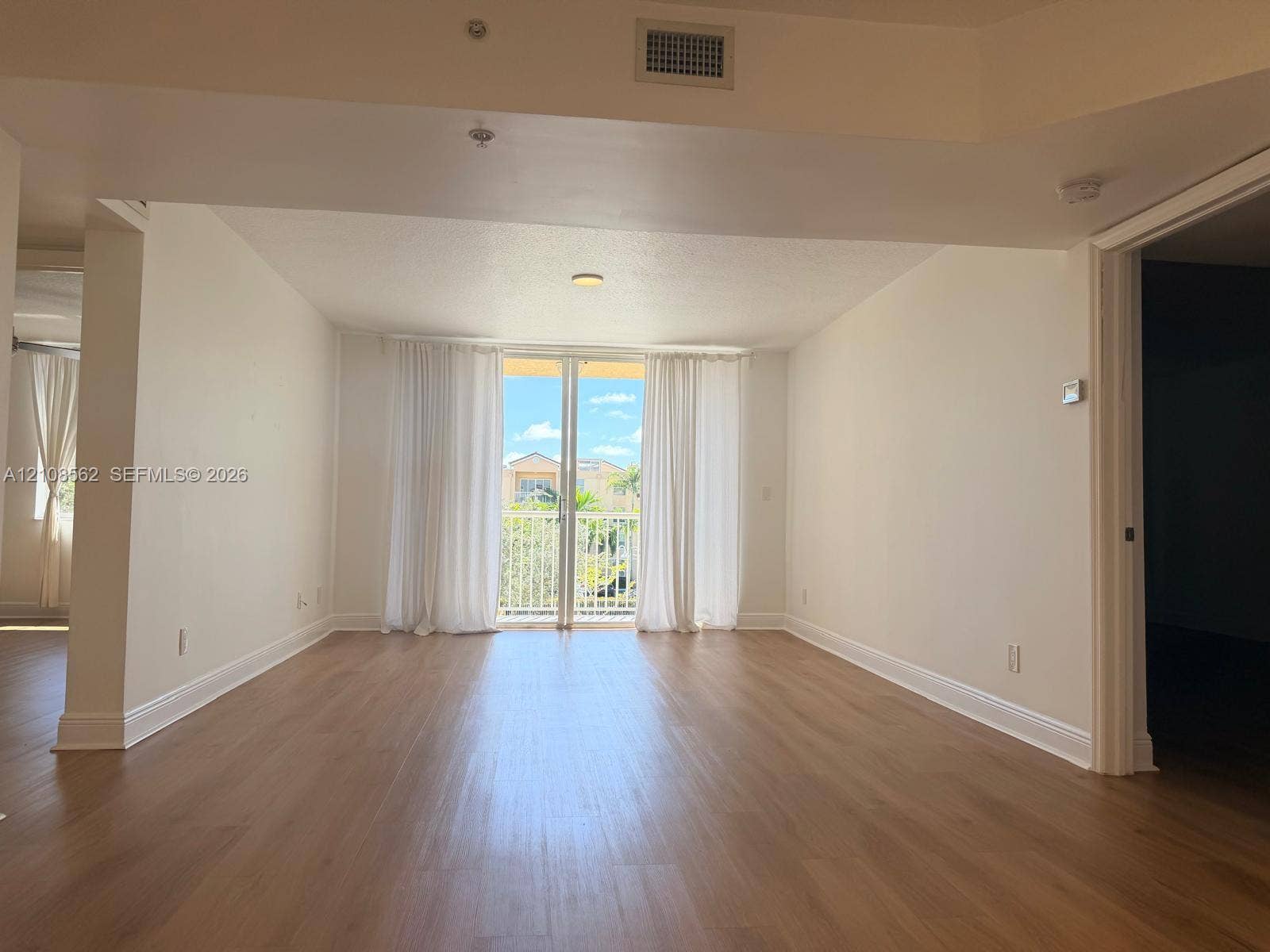 Open-concept interior with wood-finish flooring and glass sliding doors providing exterior access