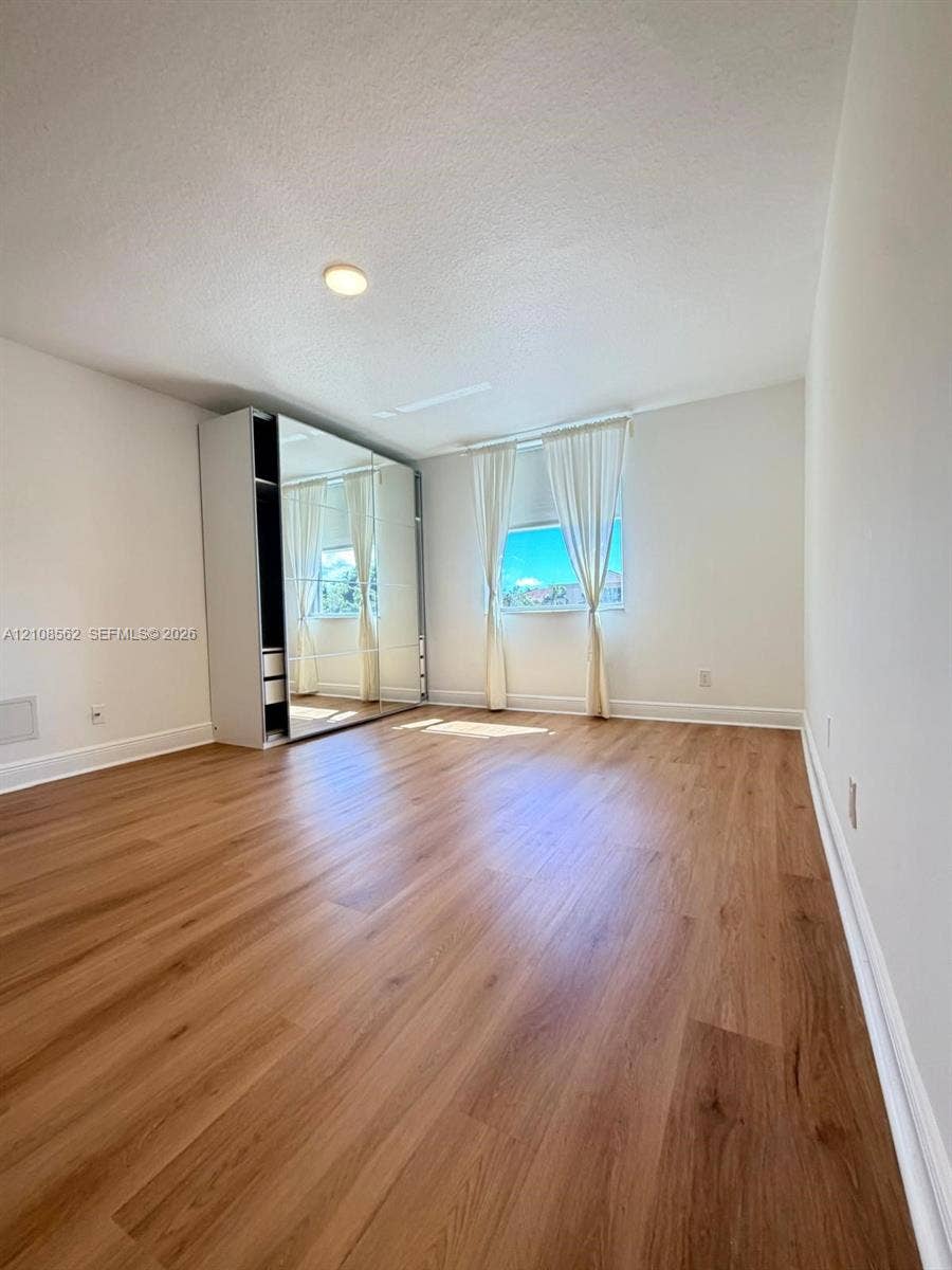 Room featuring wood-finish flooring, recessed lighting, and a built-in mirrored wardrobe