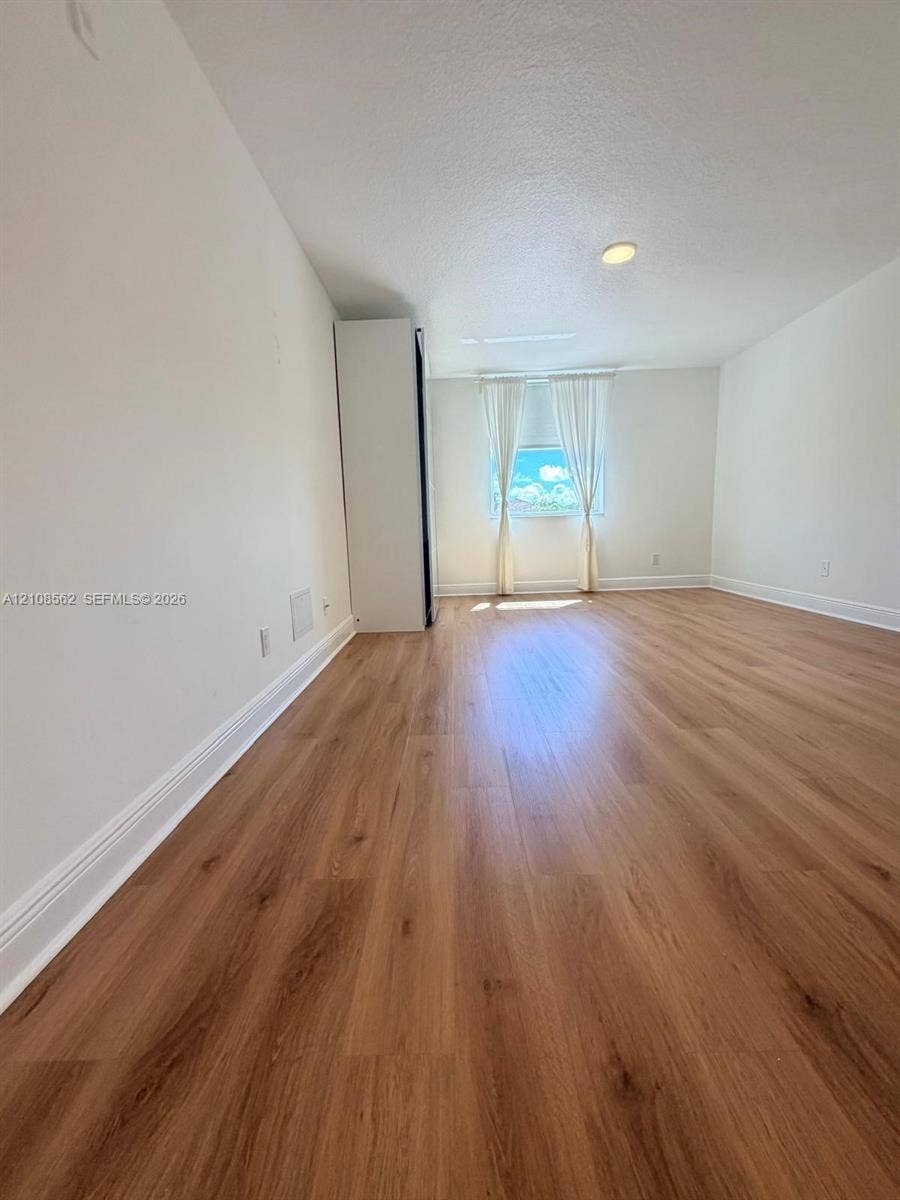 Interior space featuring wood-finish flooring, a built-in floor-to-ceiling storage cabinet, and recessed ceiling lighting