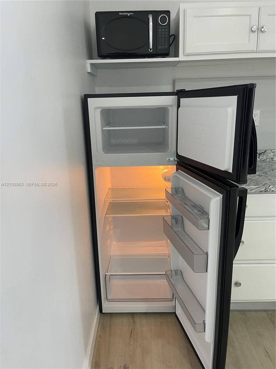14554 SW 161 Court, #Studio, Miami, Miami, FL 33196 Kitchen featuring white cabinetry, stone-finish countertops, wood-finish flooring, and a black top-mount refrigerator